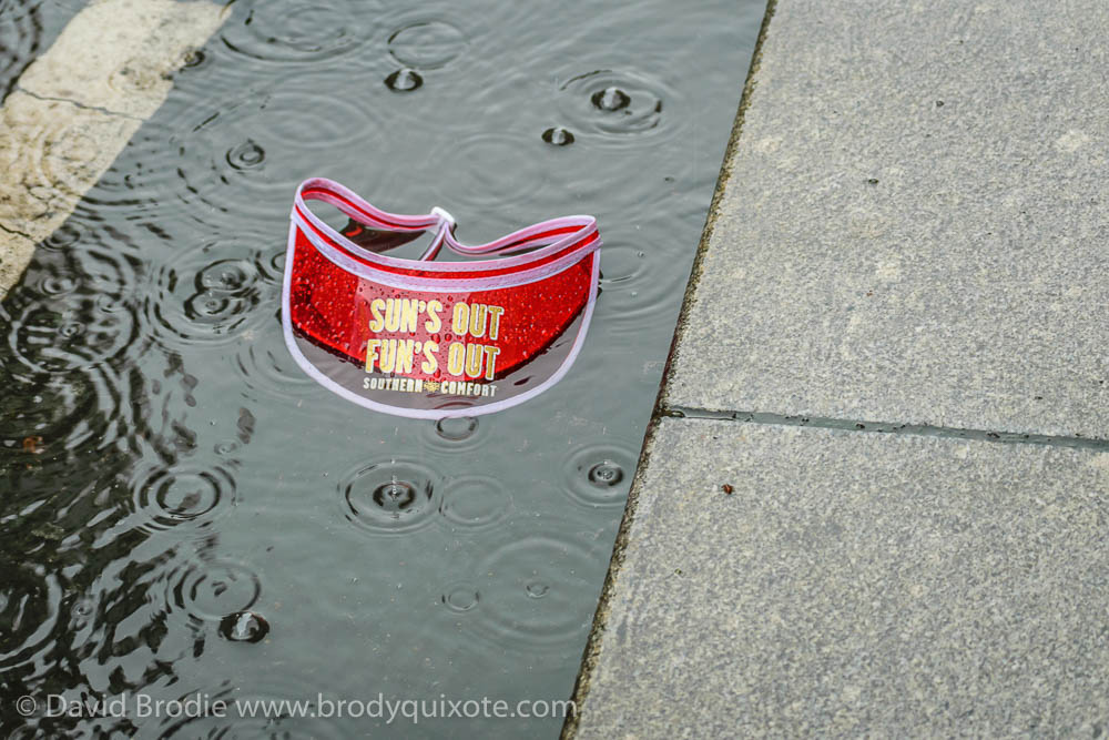 A photograph of a sun hat lying in a puddle with the slogan 'Sun's Out, Fun's Out'.